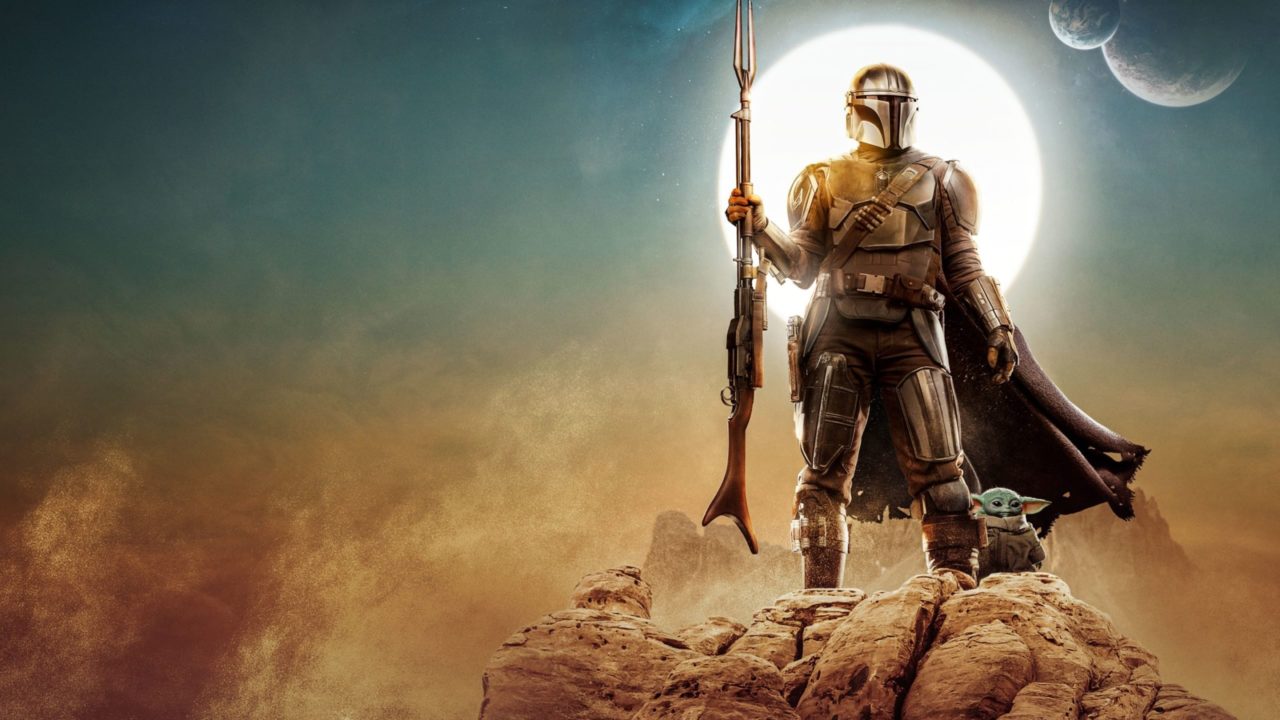 The Mandalorian and Grogu stand atop a mountain with a sun and planets in the background.
